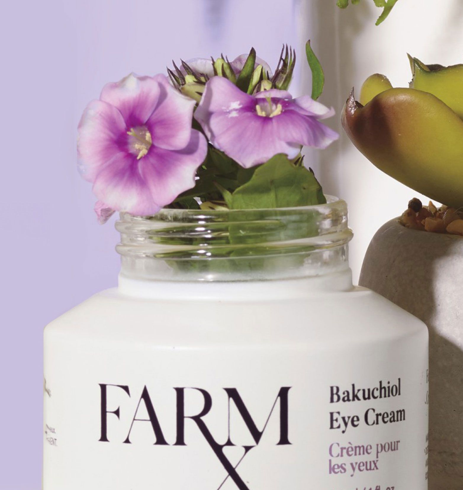 A jar of Farm RX Bakuchiol Eye Cream with purple flowers blossoming from the top of the jar.
