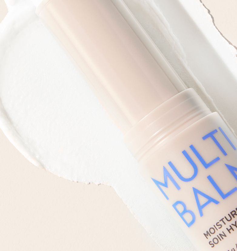 A stick of Moisture Care Multi Balm laid diagonally on top of a rich, creamy texture.