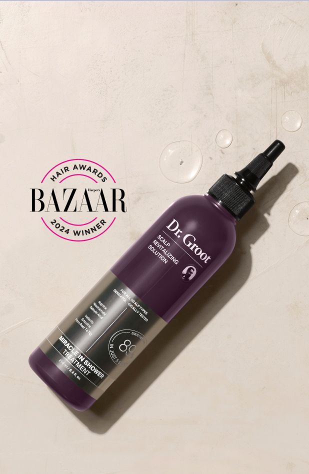 A purple bottle of Dr. Groot Miracle in Shower Treatment positioned on a textured surface, displaying a Harper's Bazaar 2024 Hair Awards Winner seal.