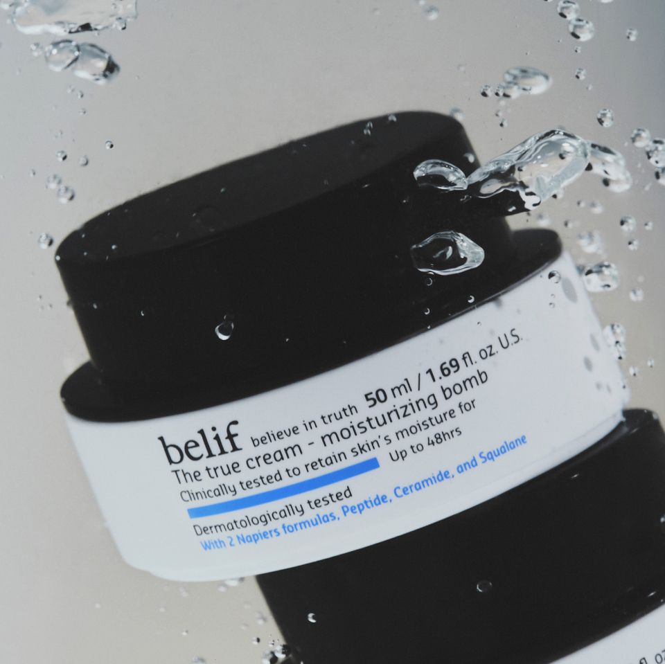 A jar of belif Moisturizing Bomb with a black lid, underwater surrounded by bubbles.