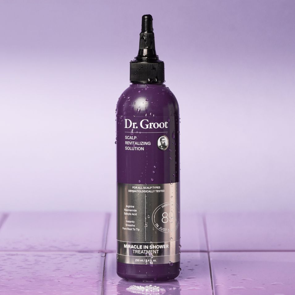 Wet purple Dr. Groot Scalp Revitalizing Solution bottle on a tiled surface.