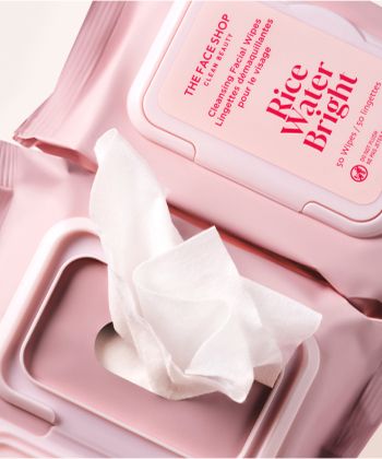 A closeup of two packs of Rice Water Bright Cleansing Wipes with one wipe coming out of a pack,