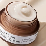 Open brown jar of white Vegan Mucin Peptide 8 Cream, labeled "firming anti-aging."
