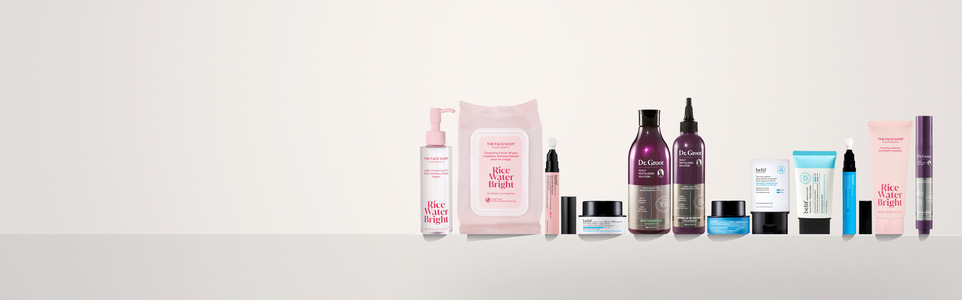 A variety of skincare and beauty products in pink, purple, blue, and white packaging, arranged on a light surface.