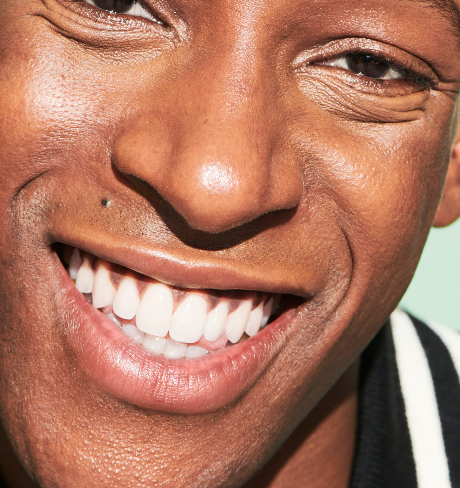 A male model is smiling, looking at the viewer - his teeth looking clean, shiny and healthy after using the Reach POP Floss