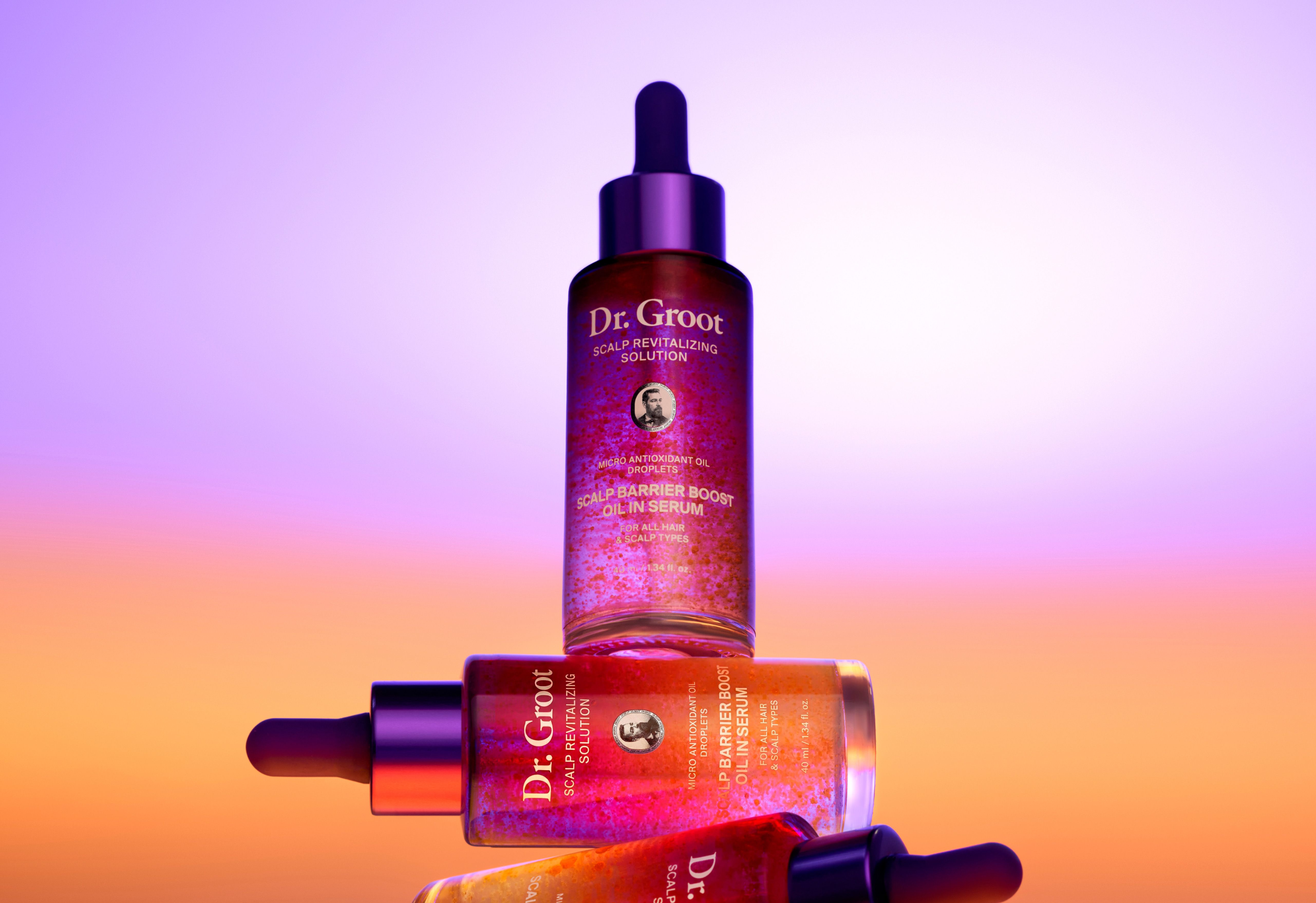 Three Dr. Groot Scalp Barrier Boost Oil in Serum bottles, reddish-orange with visible droplets, stacked against a purple to orange gradient background.