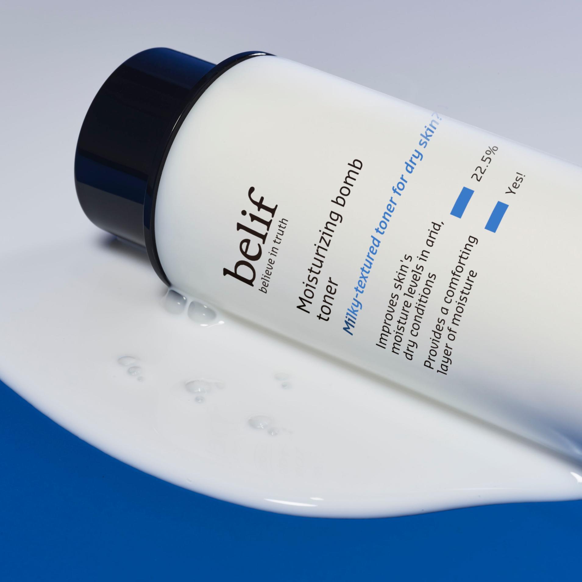 A tube of belif moisturizing bomb toner rests on a small pool of skincare product.