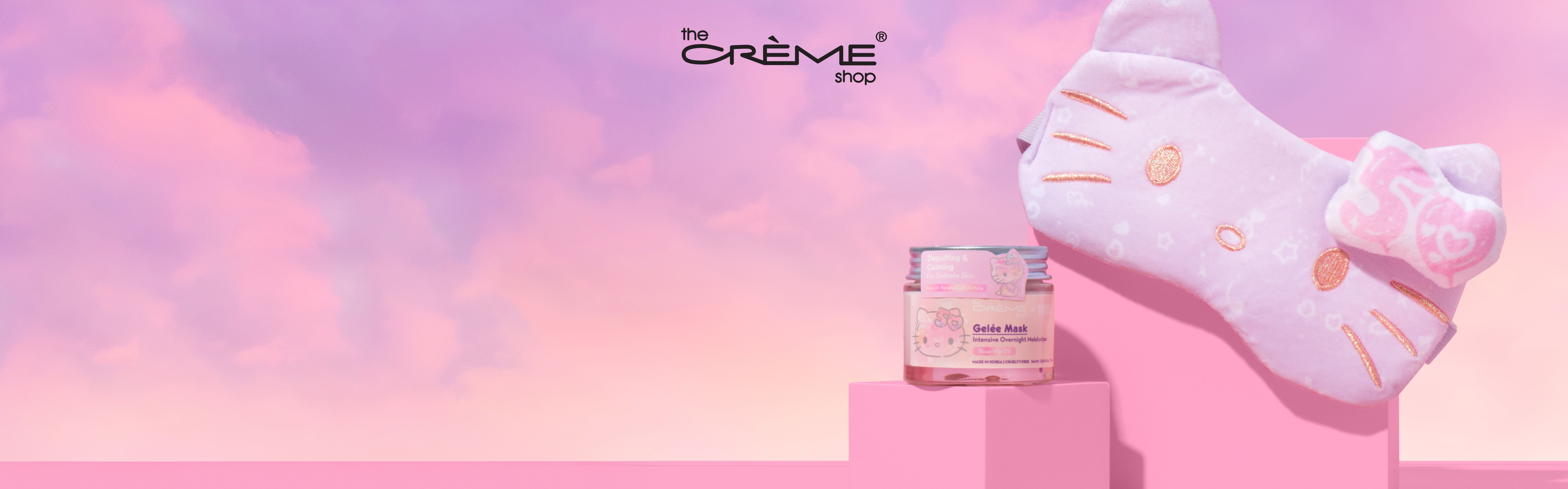 The Creme Shop x Hello Kitty 50th Anniversary Collection ad featuring the Plushie Sleep mask on a pink square block, behing the Gelee Mask on another smaller square block.