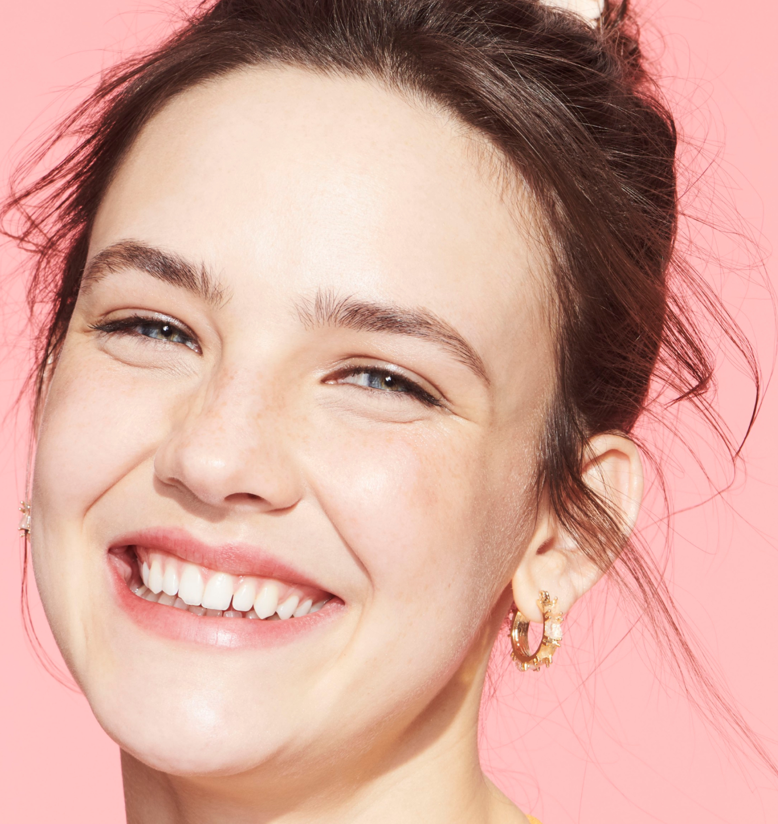 A brunette model looking right at the viewer, smiling with her perfectly white and healthy teeth