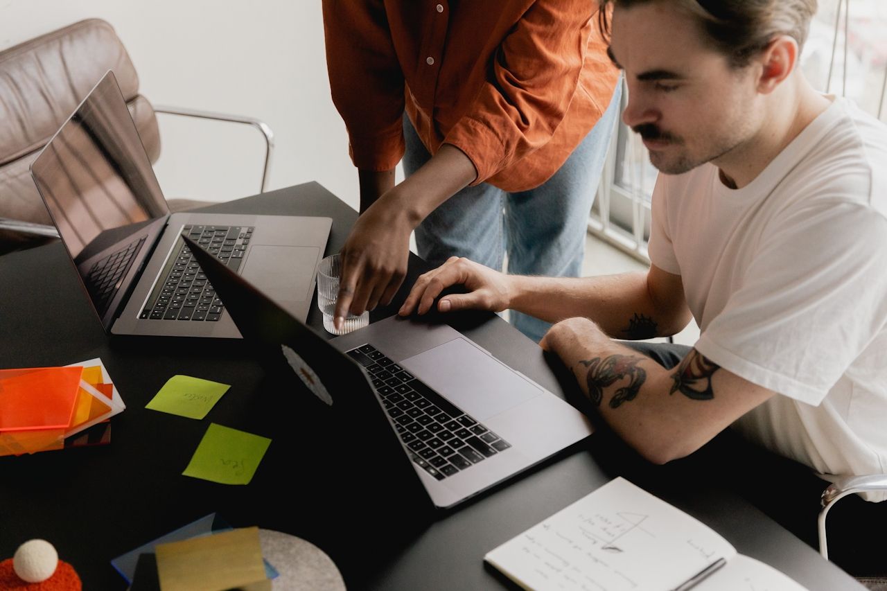 2 workers hovering over laptop