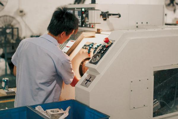 Factory worker adjusting controls on a CNC machine