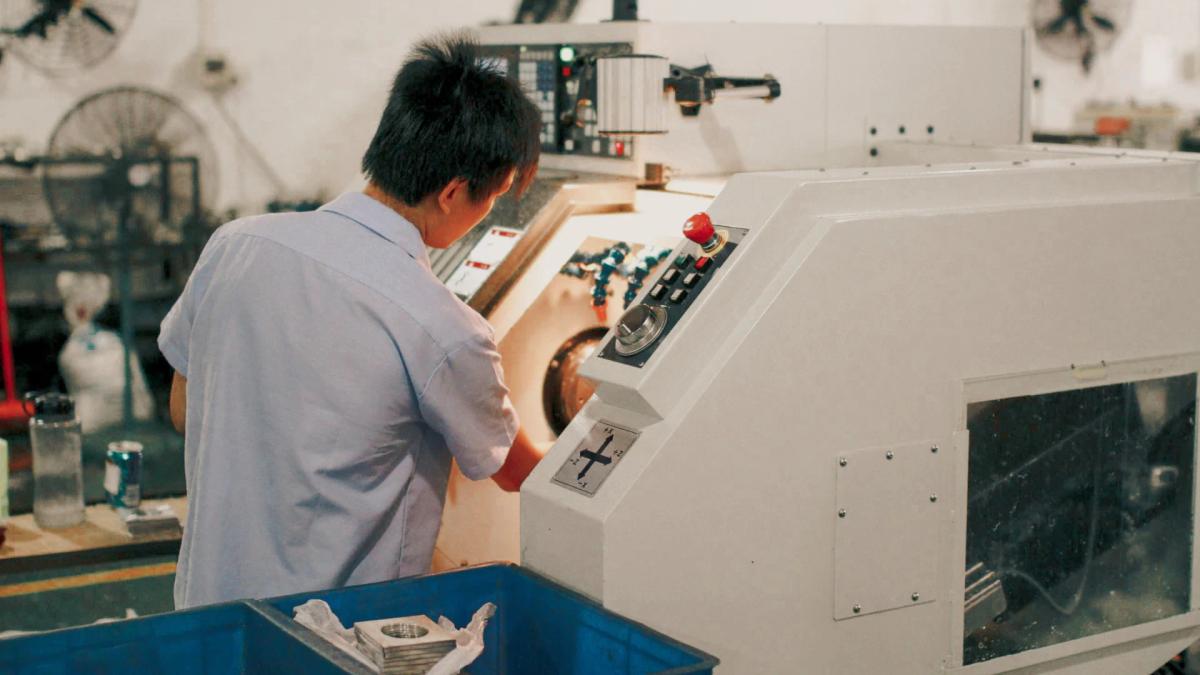 Factory worker adjusting controls on a CNC machine