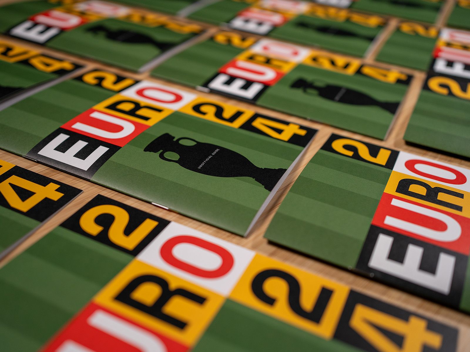 Angled close-up of multiple Euro 2024 guide covers with bold lettering and trophy silhouettes.