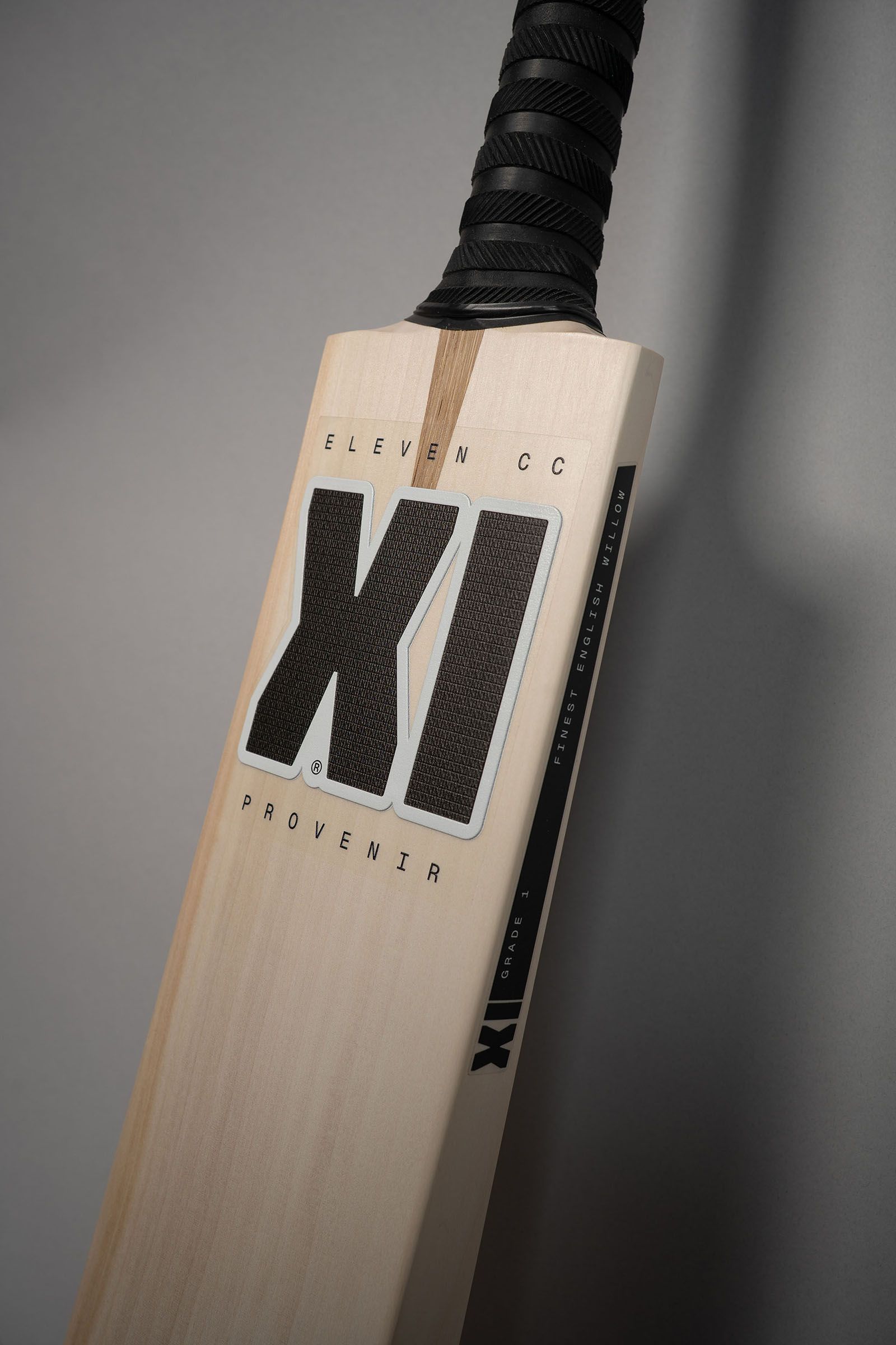 Front of an Eleven Cricket Club willow bat with its large black XI mark against grey.