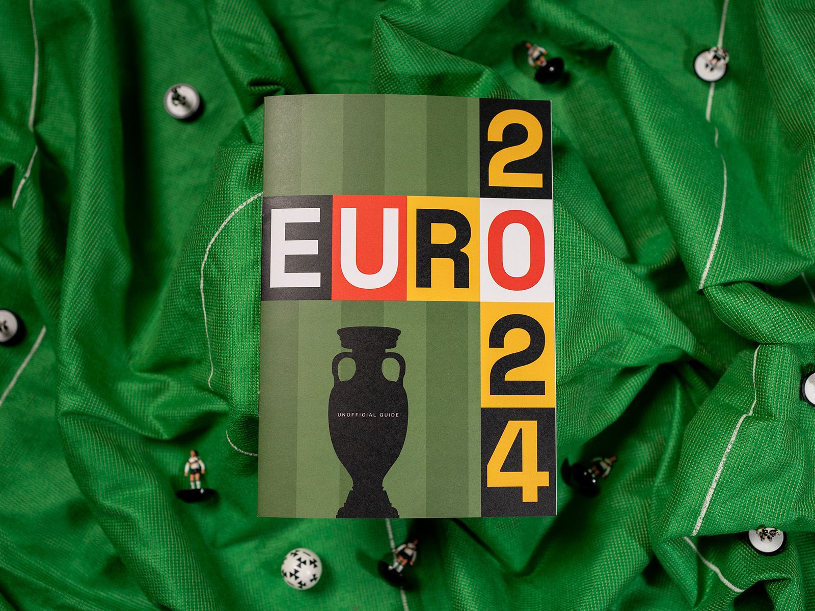 Euro 2024 unofficial guide with a colourful typographic cover resting on green football shirts.