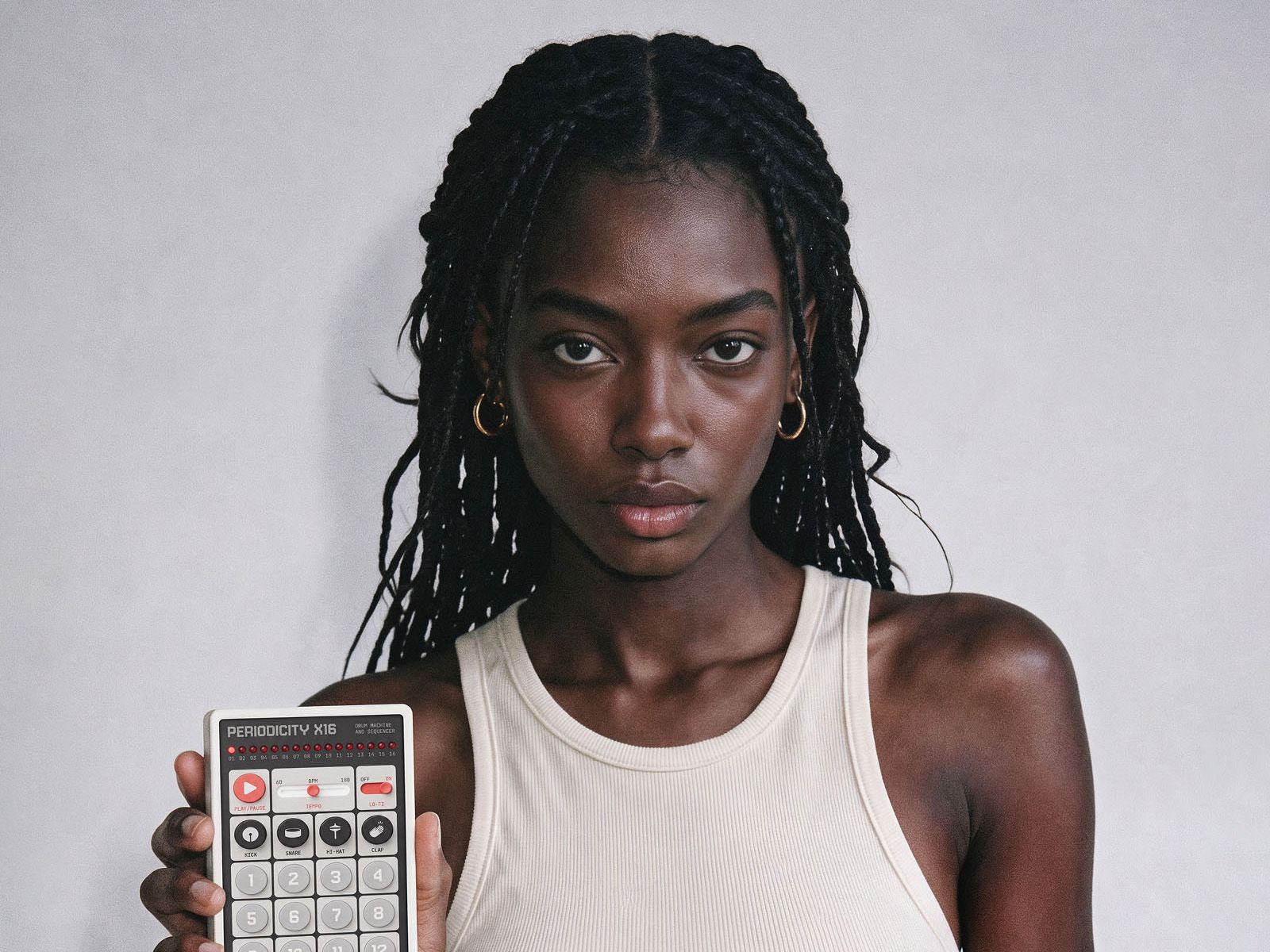 Periodicity X16 drum-machine interface held by a woman in a white top.
