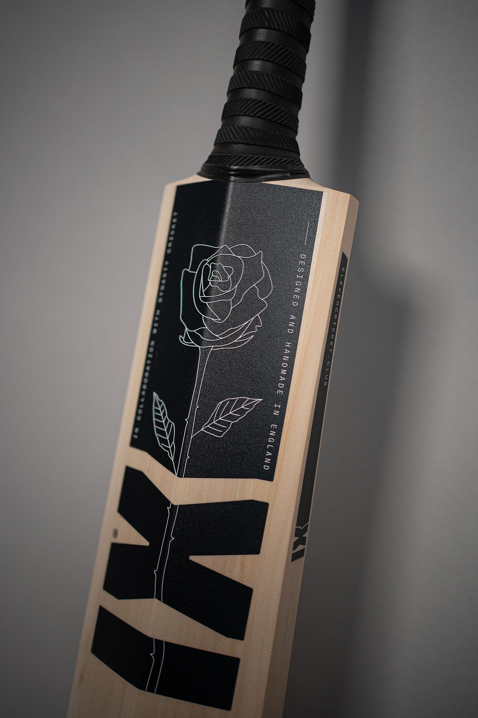 Reverse of an Eleven Cricket Club bat with a dark decorative label and bold geometric XI graphics.