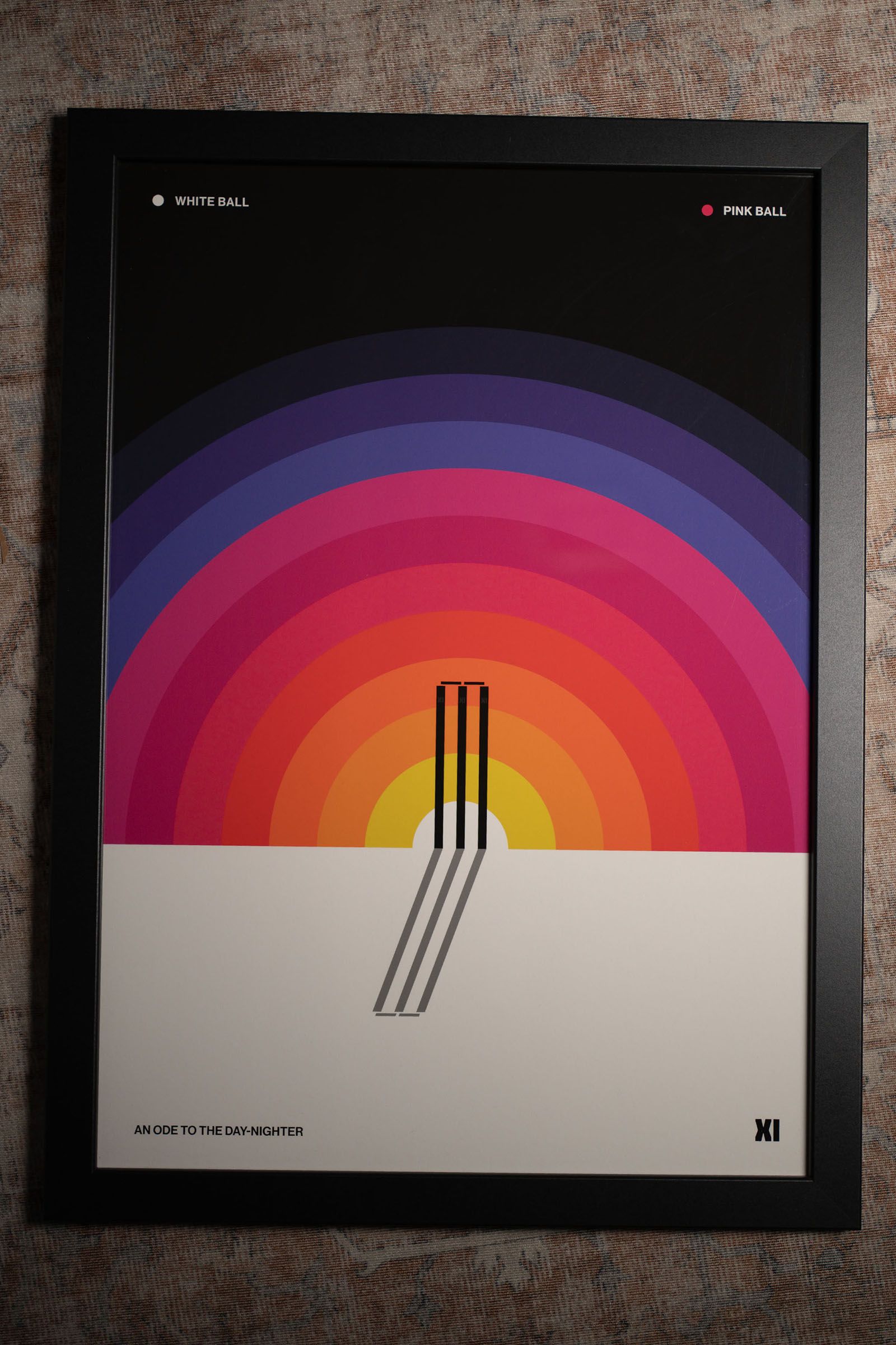 Framed cricket poster showing a black stump motif against concentric bands of bright colour.