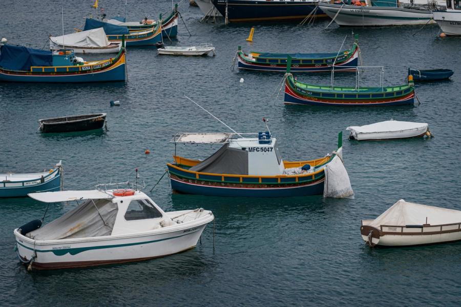 A fleet of traditional Maltese luzzu boats moored in a harbour
