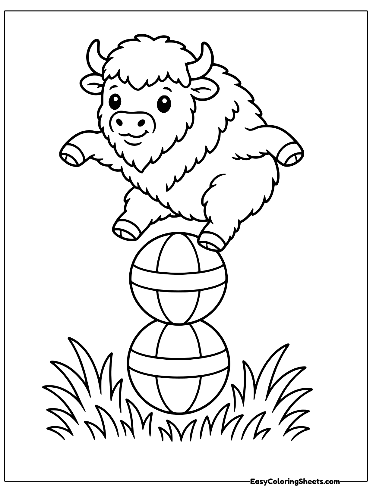A playful bison balances on top of two stacked striped balls in a grassy field.