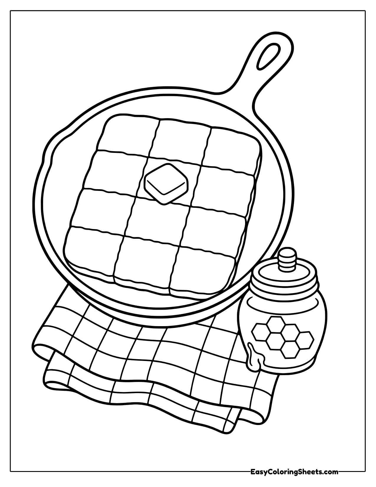 Cornbread in a cast iron skillet with butter and a honey jar