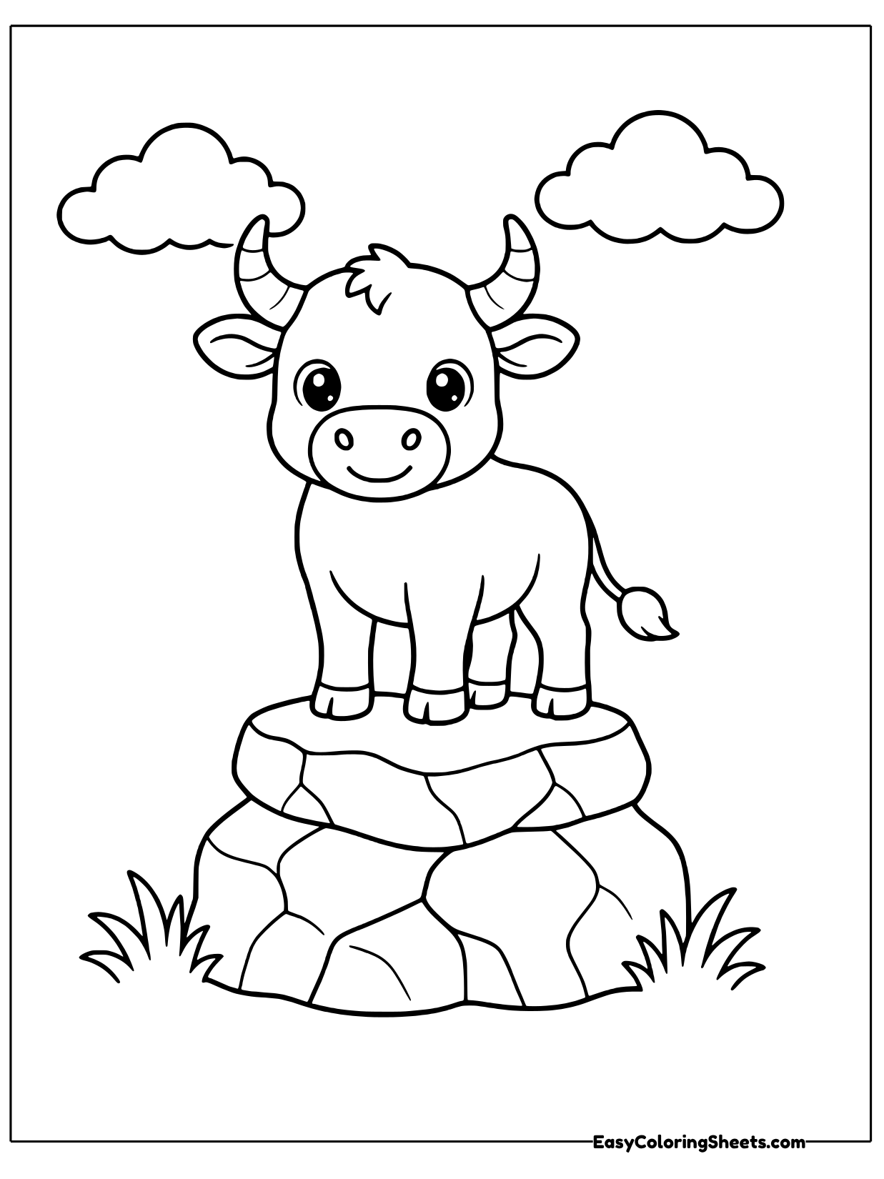 A cute bull stands on top of a rounded pile of stacked rocks, looking out under a cloudy sky.