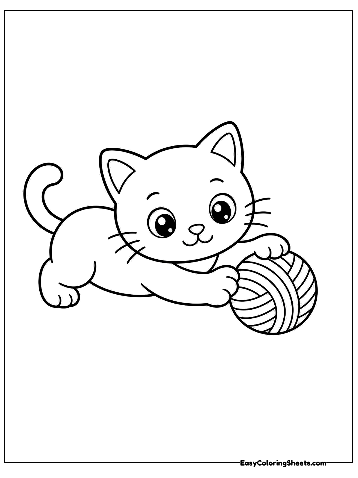 A kitten crouches low with its front paws stretched toward a ball of yarn, ready to pounce.