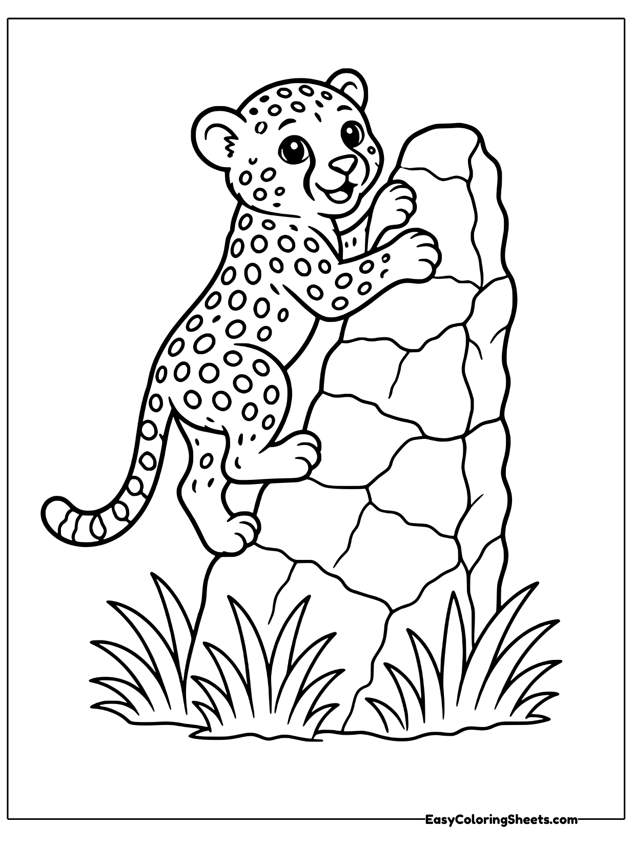 A cheetah cub reaches up and climbs the side of a tall rock with grass at its base.
