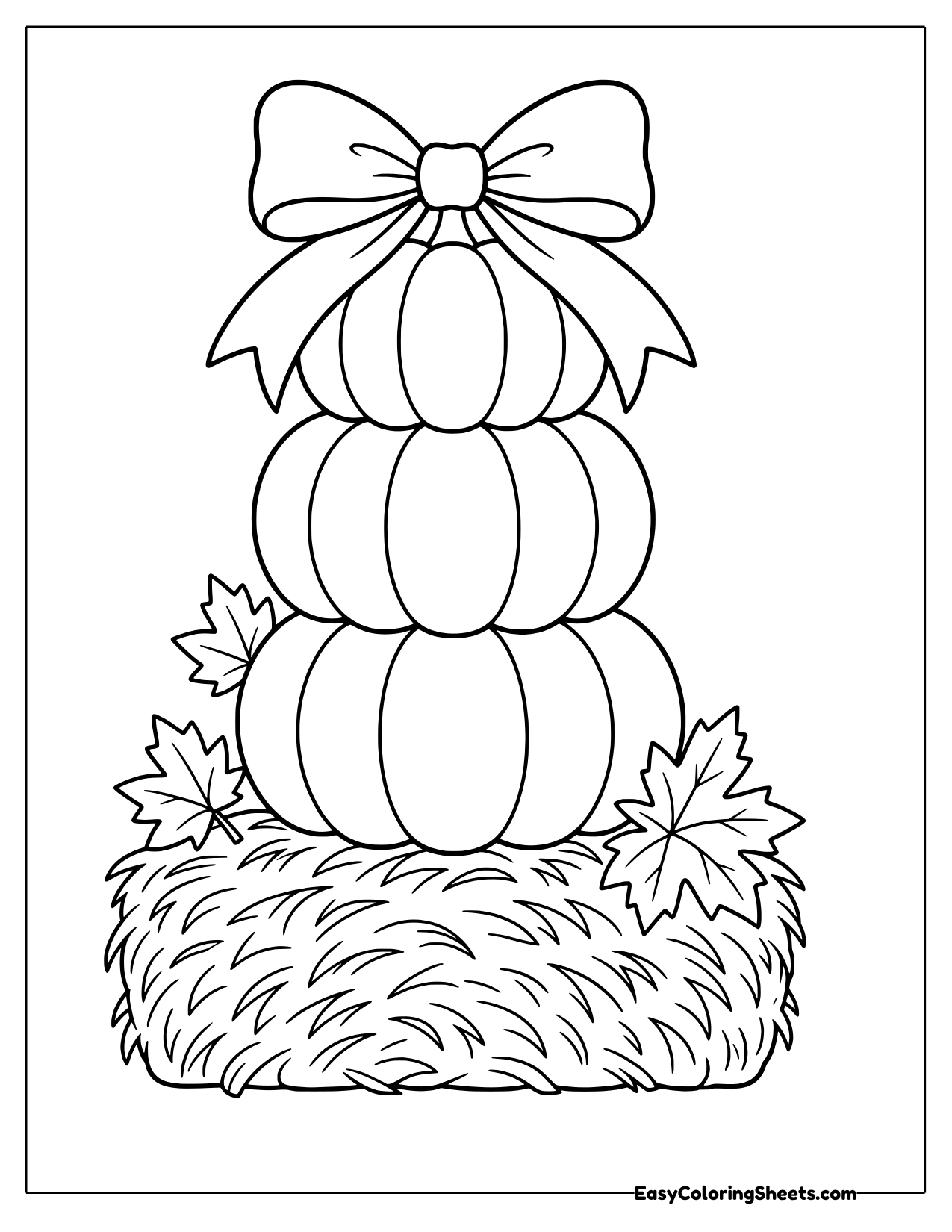 Stack of three pumpkins with a bow on a hay bale