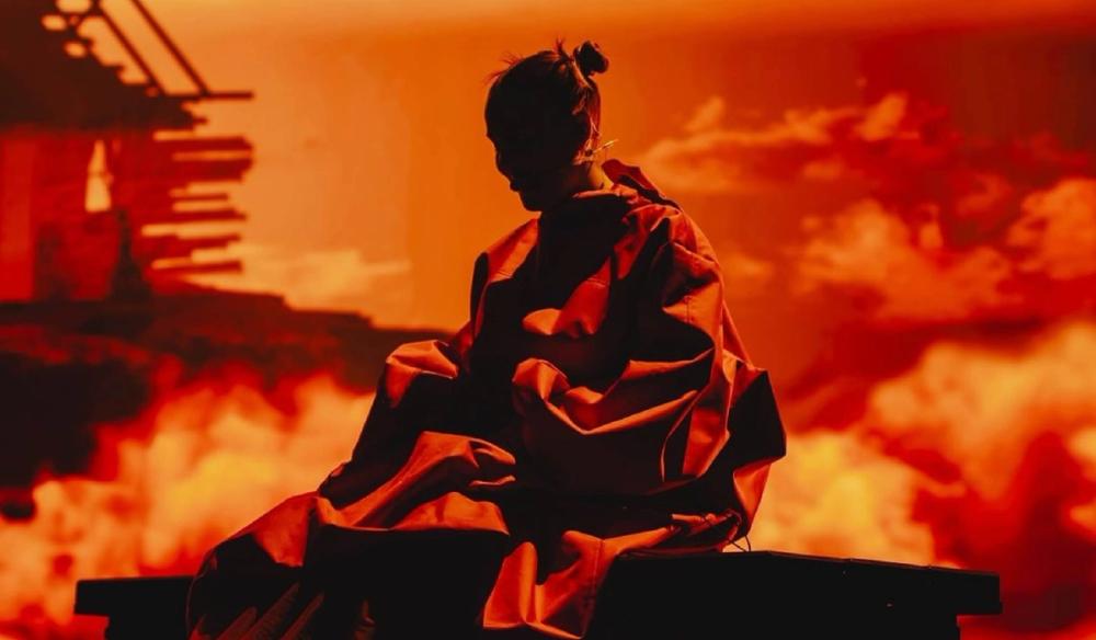 Anne-Marie sits silhouetted agains an orange sky background