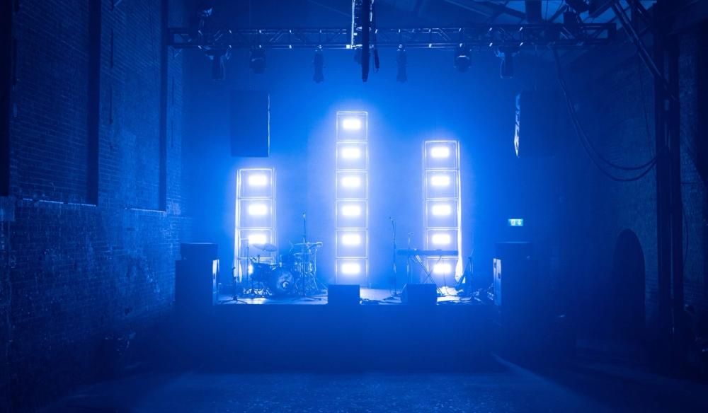 3 light towers, lit in blue, on a stage in an asymmetric formation