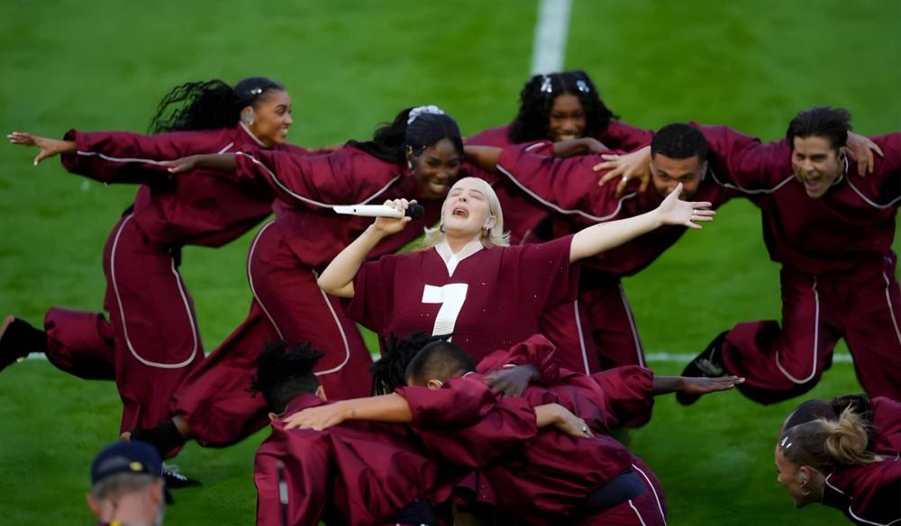 Anne-Marie performs on the rugby pitch, with her dancers in a scrum around her