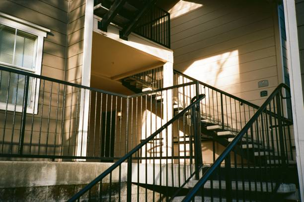An exterior apartment stairwell with metal railings, lit by low evening sunlight.
