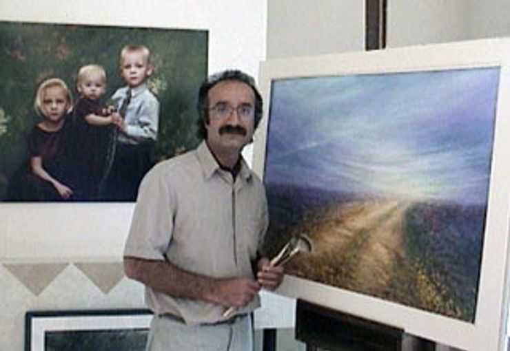 Der Künstler, Behruz Bahadoori, mit Pinseln vor zwei Gemälden.