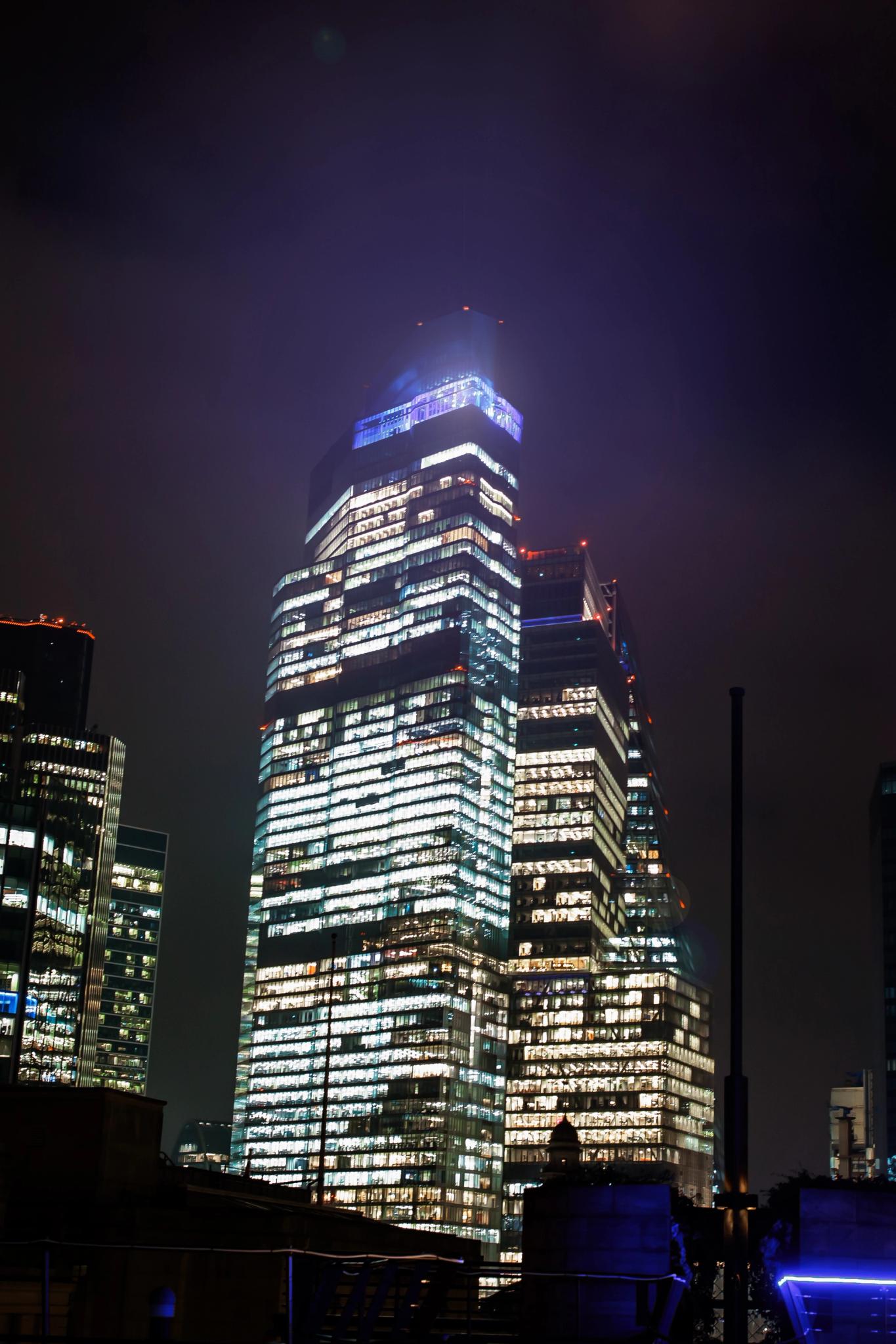 Female musician in a reflective sequin dress playing a saxophone on stage under bright blue and white beams of light