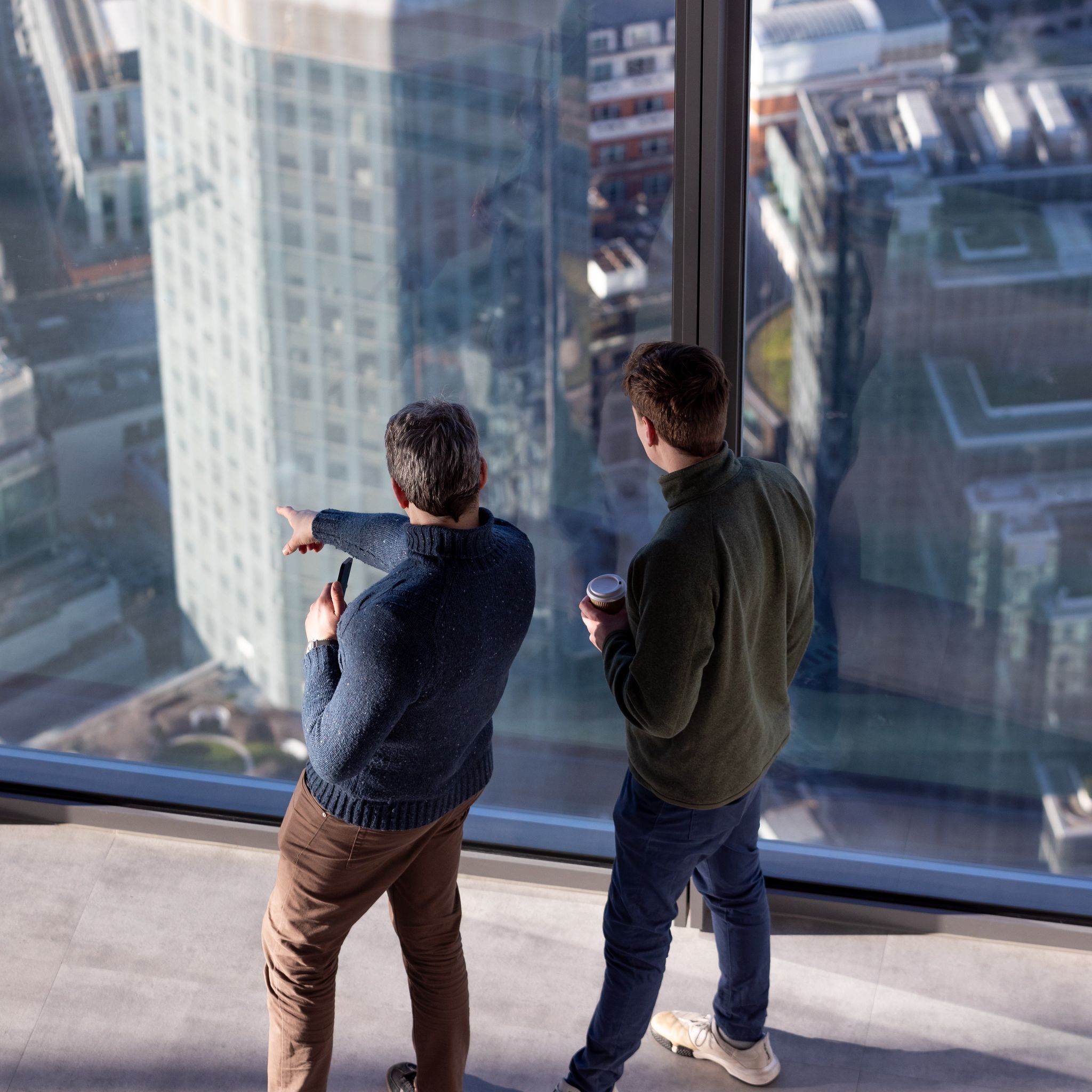 Men with coffee cups looking out window