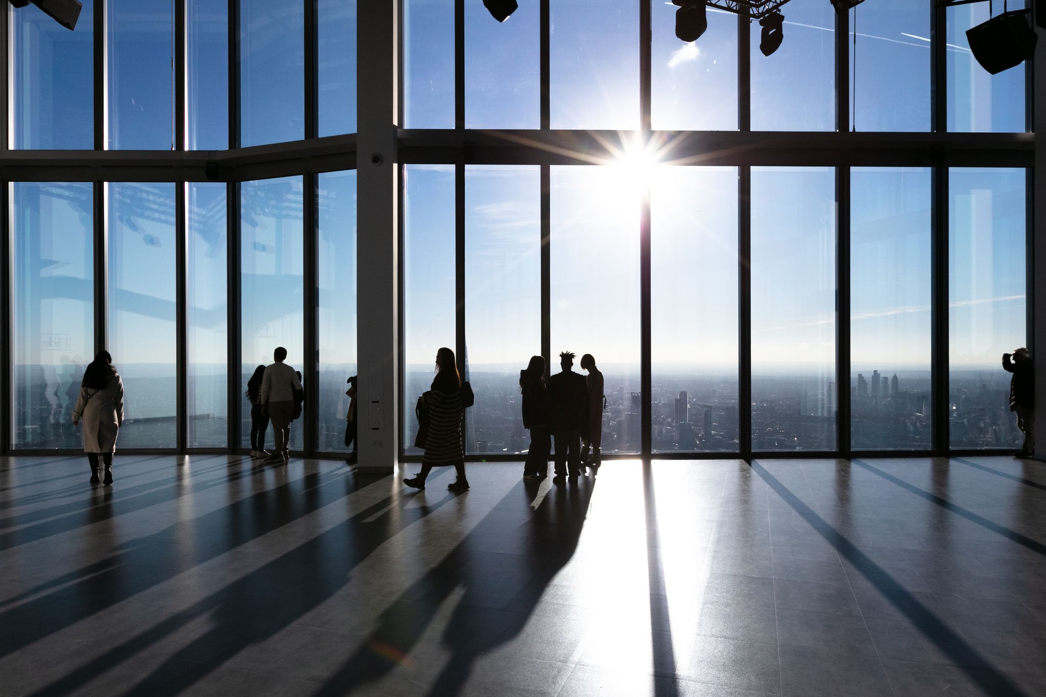 People standing next to large glass windows with a view of the London skyline