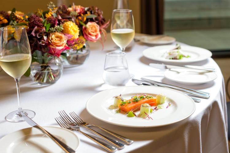 Wine glass being filled in front of plate of food