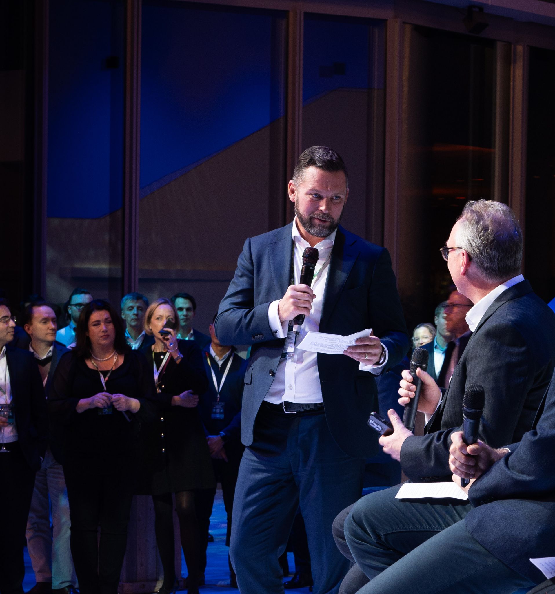 Man speaking on a microphone in front of crowd