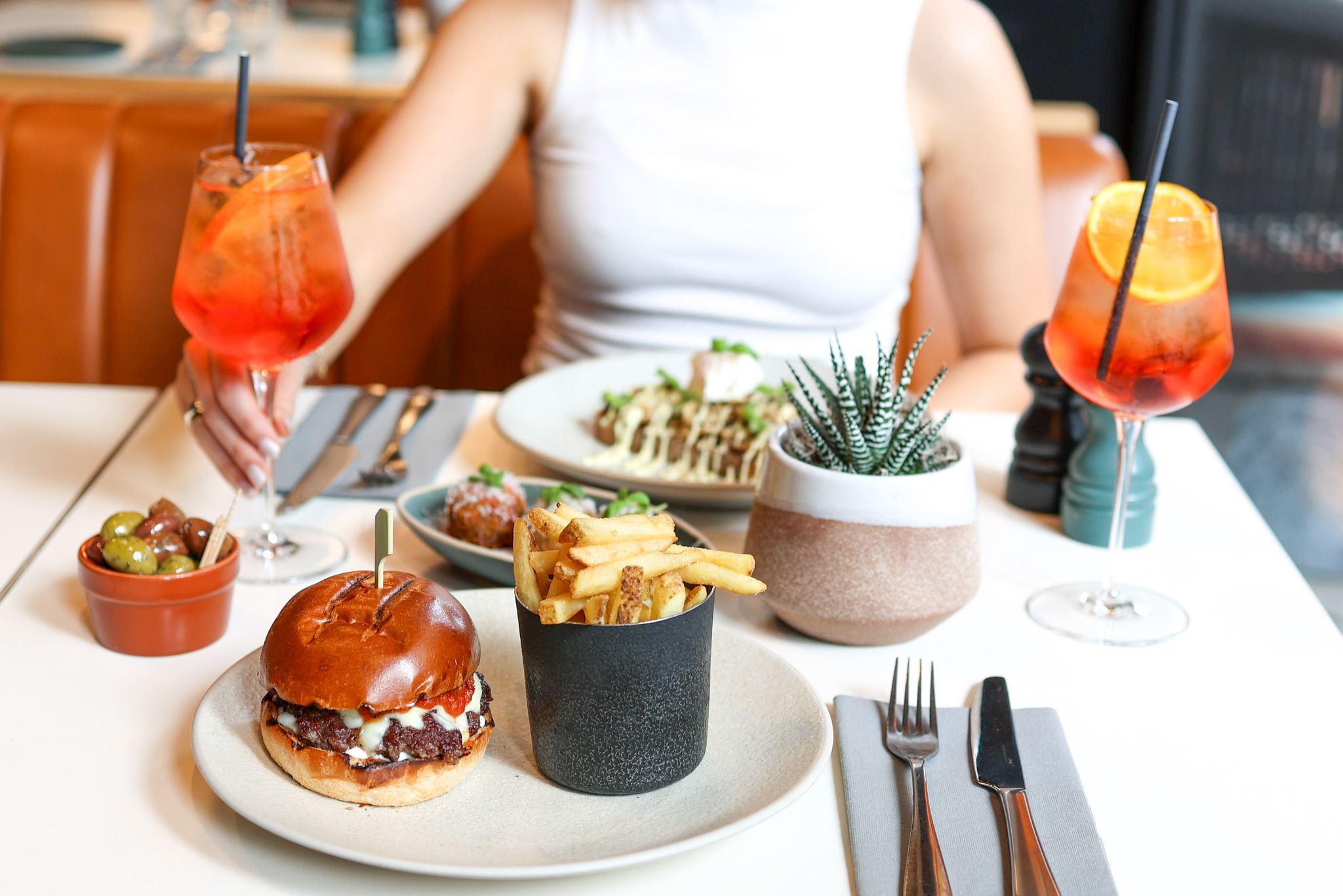 Lady sitting at a table with food and orange drinks