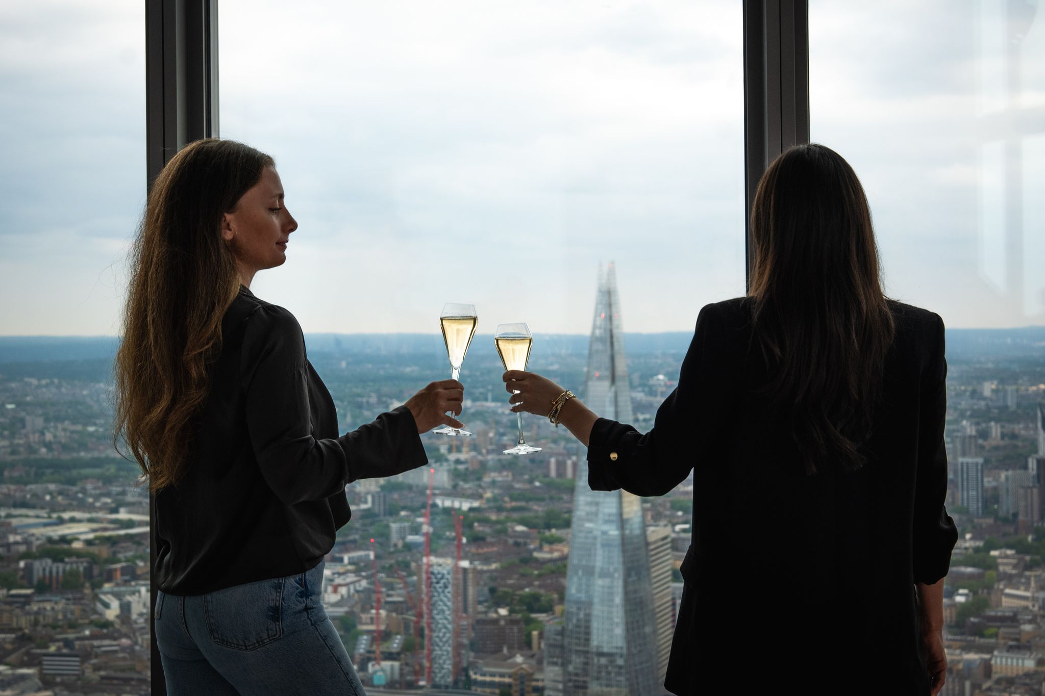 Two women with glasses of bubbles overlooking The Shard