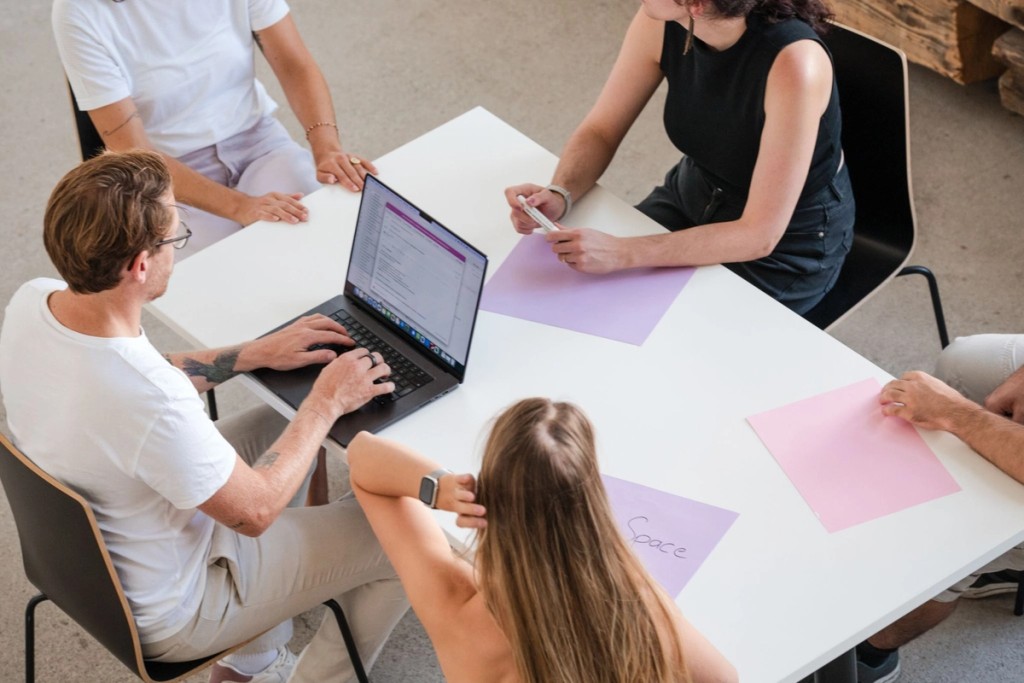 Eine Gruppe an Menschen rund um einen Tisch in einem Meeting