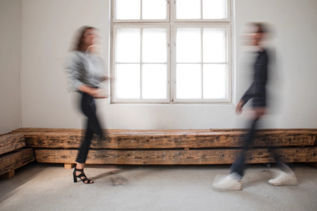 2 verschwommene Menschen gehen aufeinander zu in einem hellen Raum