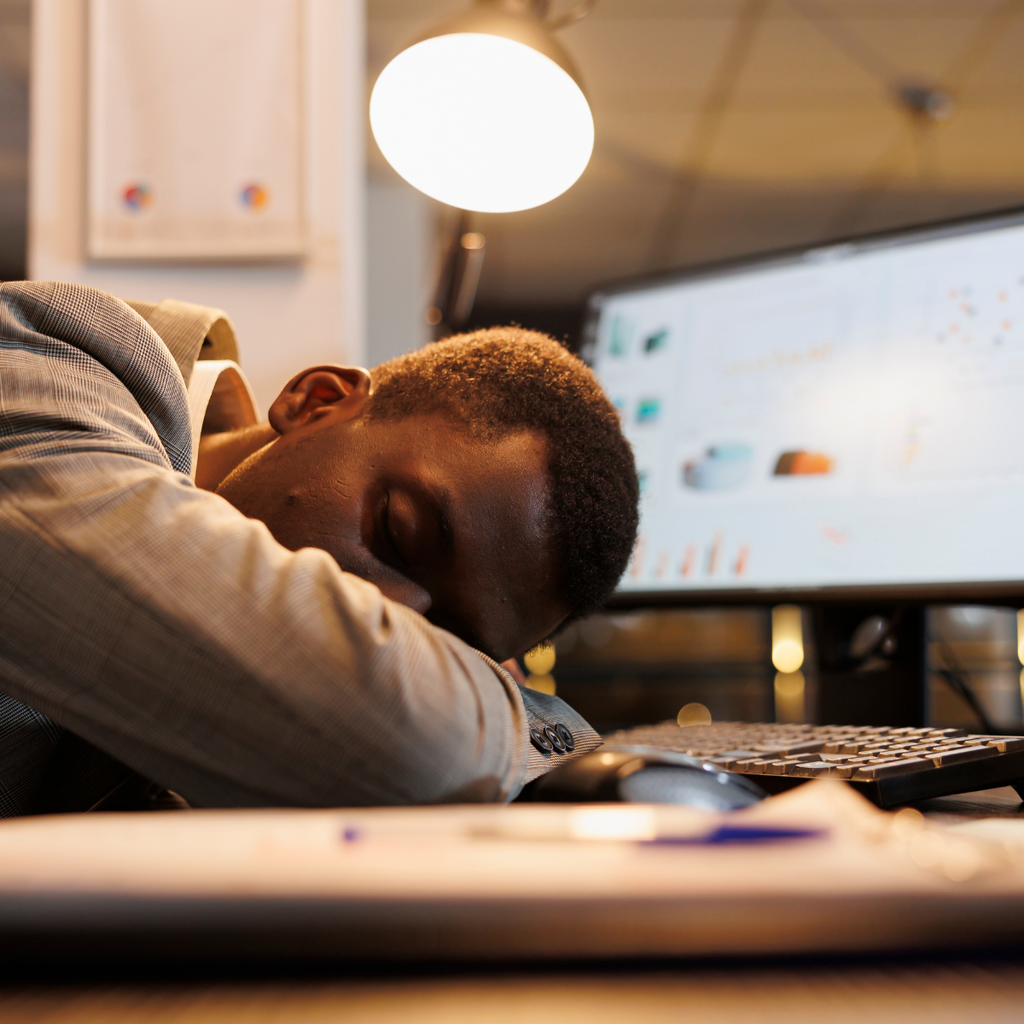 Mann schläft auf Bürotisch