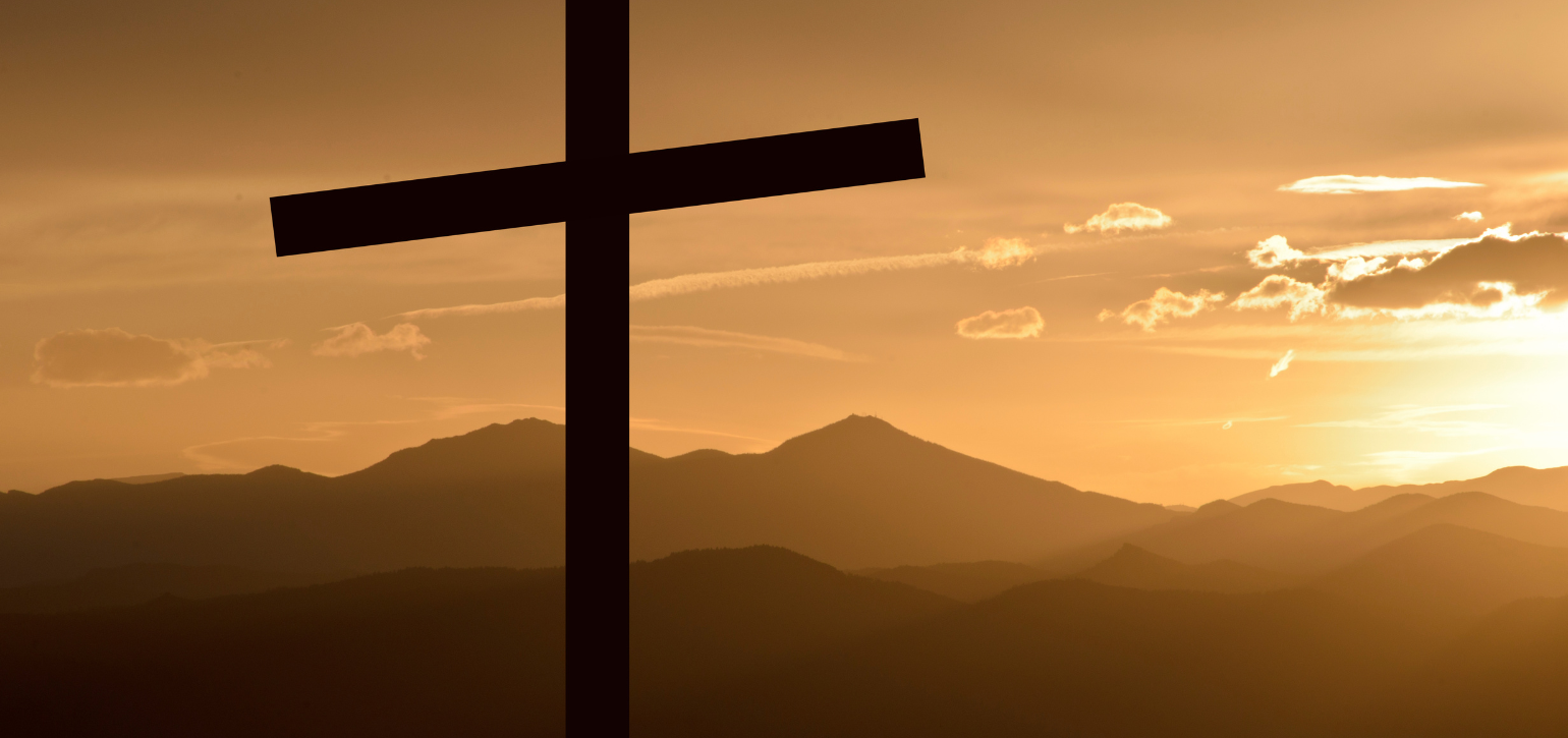 crucifix on a hill in sunset with mountains in background