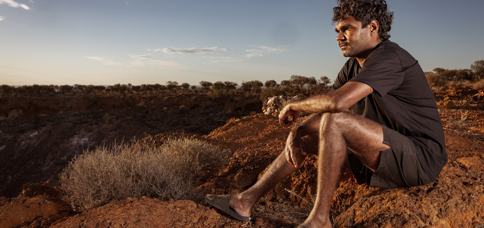 aboriginal man sitting on hill