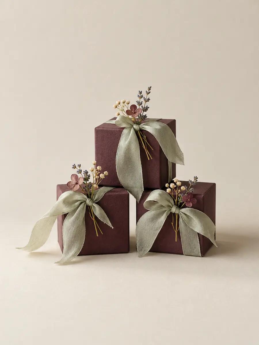 Plum favour boxes tied with sage silk ribbon and pressed sprigs