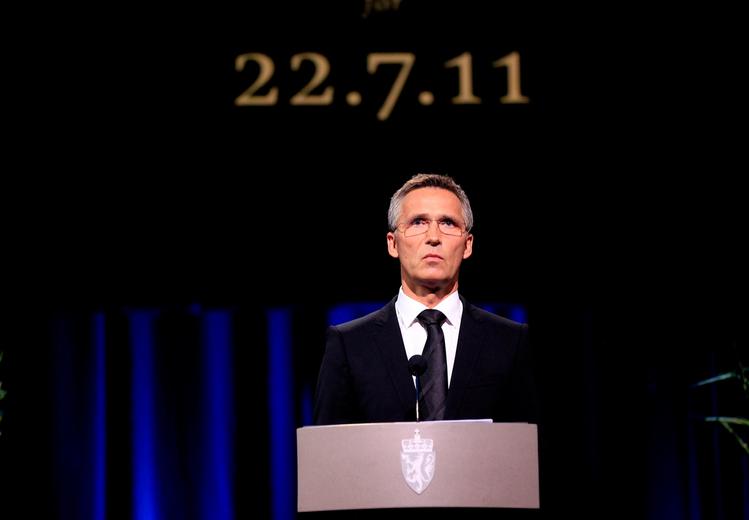 Suited man on lectern. In the background a wall with the inscription "22.7.11".