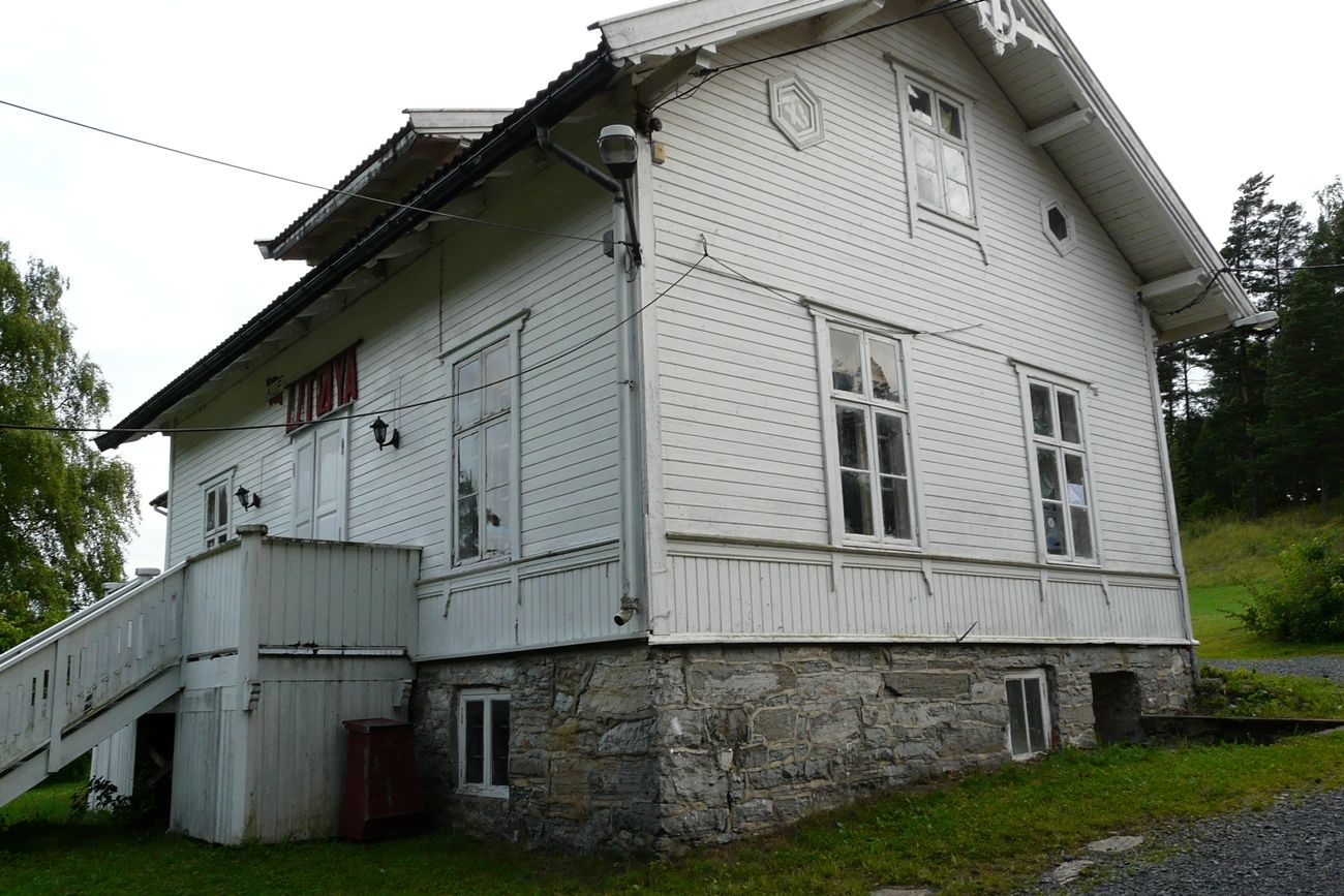 White house with grass around. Staircase and sign with the text "Utøya" in red.