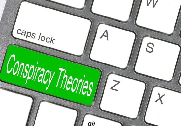 Section of a PC keyboard with white buttons. One of the buttons on the keyboard is green with the text: Conspiracy Theories. Illustration
